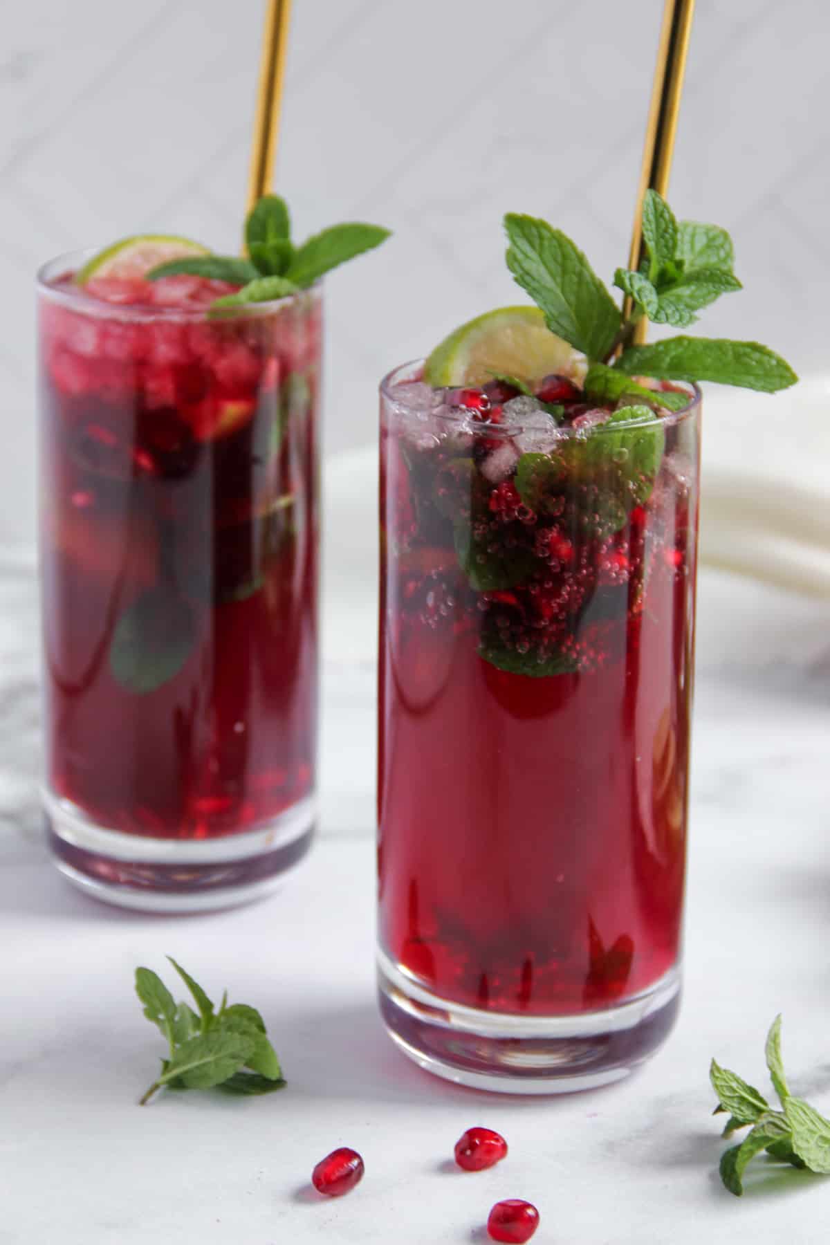 pomegranate mojito garnished with mint sprigs and served in 2 glasses