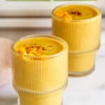 mango thandai served in 2 glasses topped with diced mango and saffron