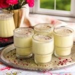 Thandai served in 4 cups garnished with rose petals and pistachios