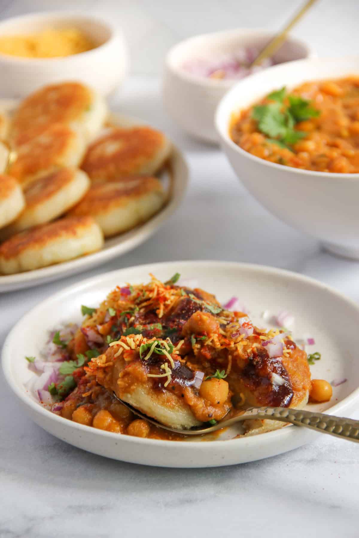 ragda patties served in a white plate  garnished with sev and cilantro