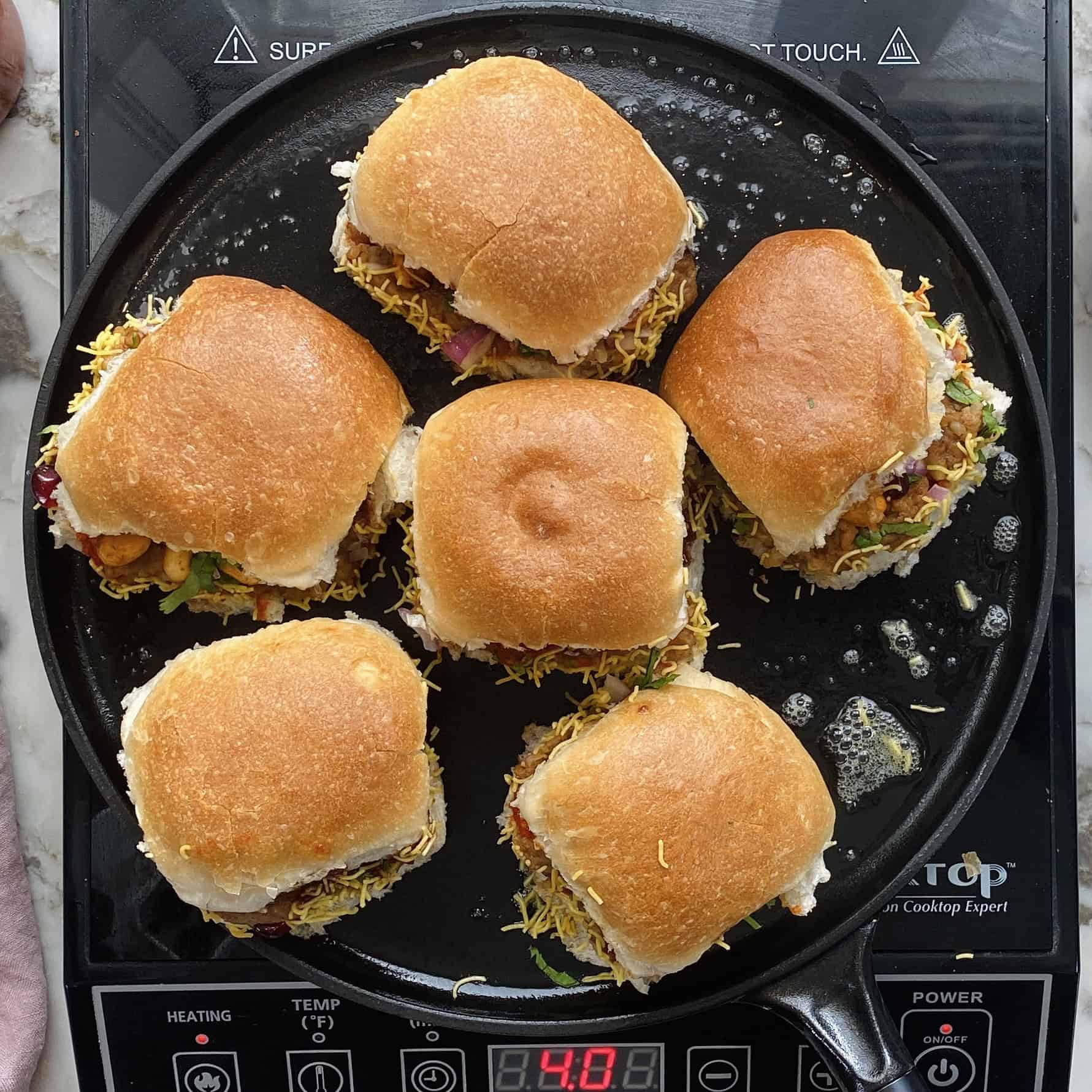 Toasting Dabeli on a tawa with butter.