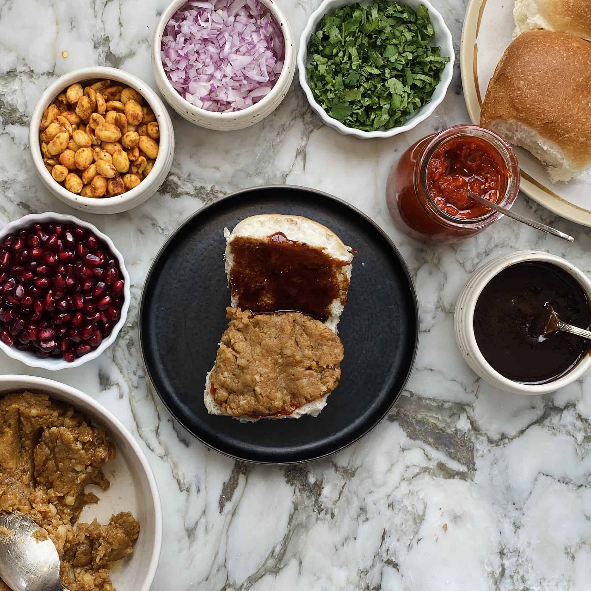 potato filling placed over red chutney on the bun.