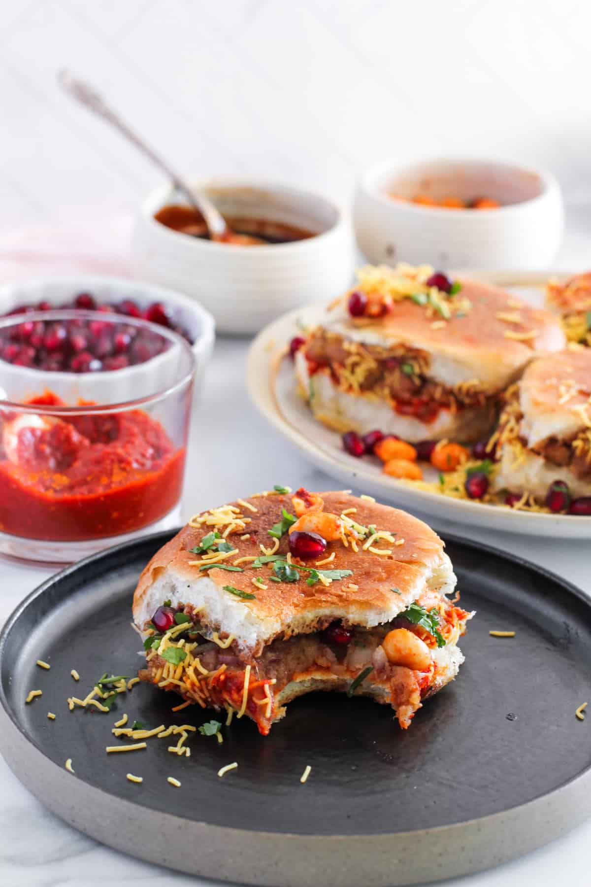 Kutchi Dabeli on a black plate with a bite taken 