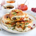Dabeli in a serving platter garnished with sev, cilantro, pomegranates and peanuts