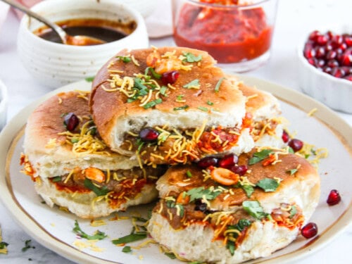 Dabeli in a serving platter garnished with sev, cilantro, pomegranates and peanuts