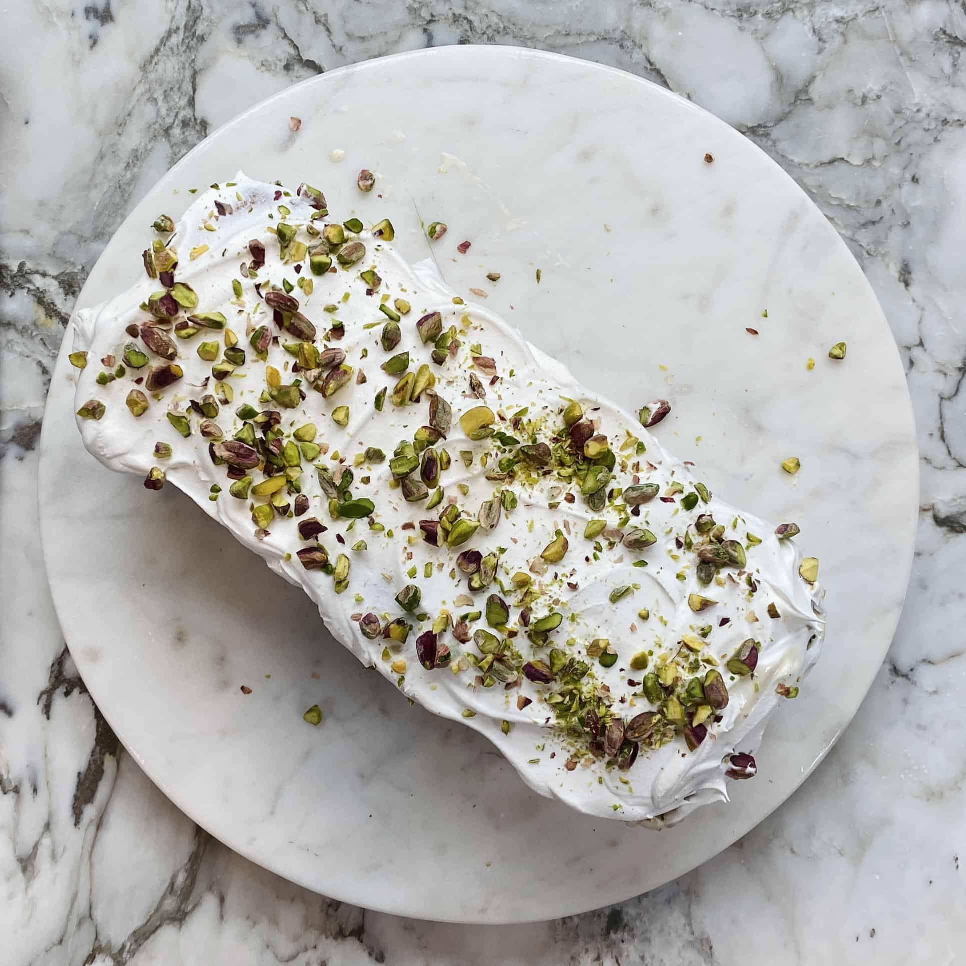 frozen ice cream cake topped with whipped cream and pistachios 