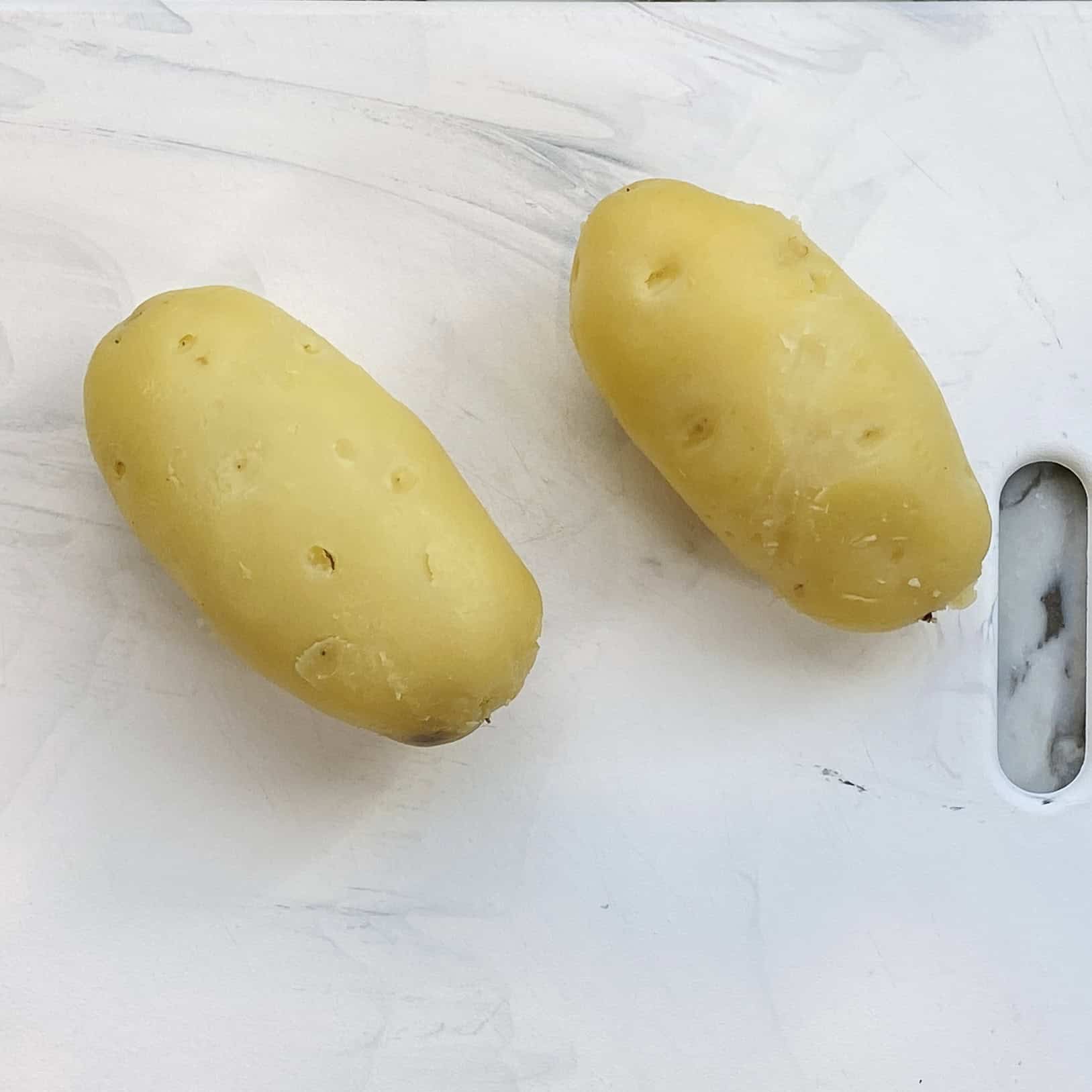 peeled potatoes on a cutting board.