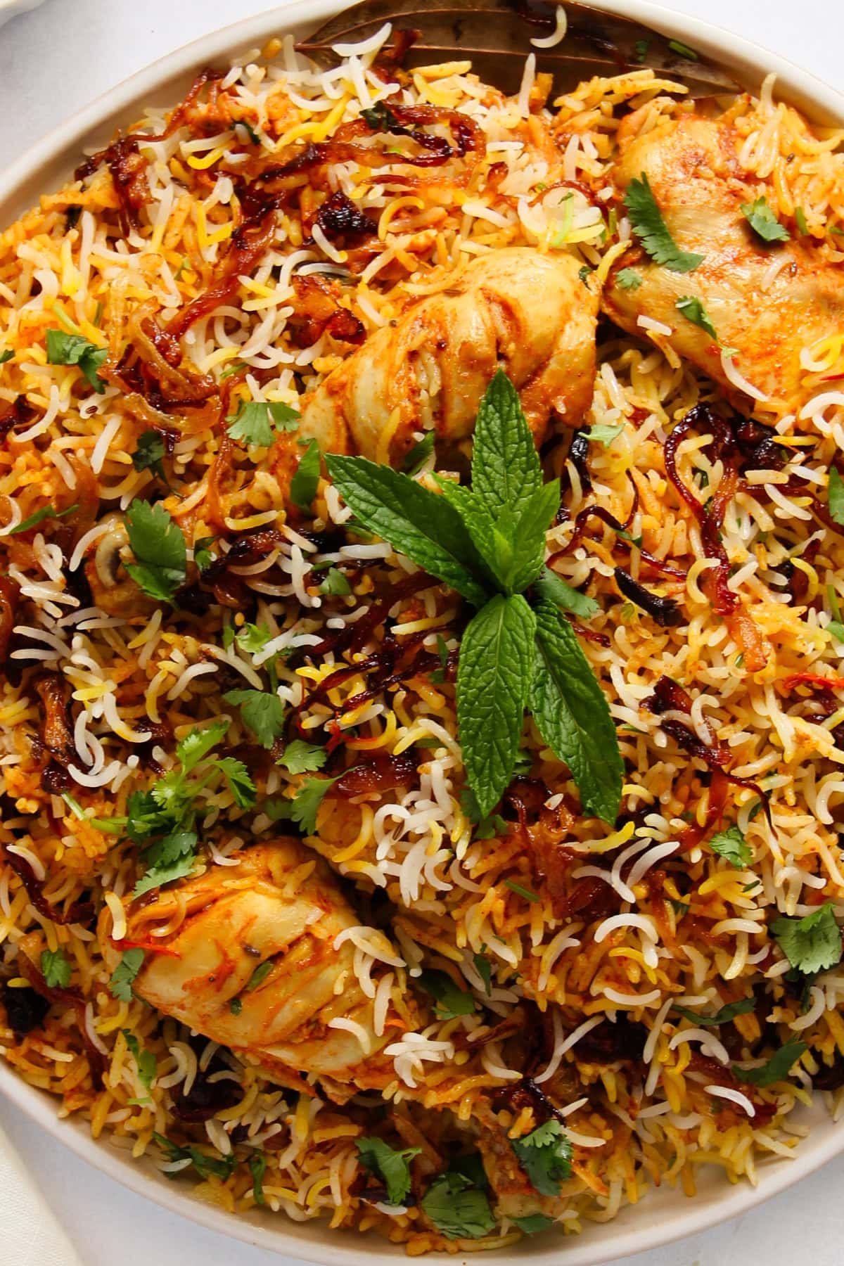 chicken biryani garnished with a mint sprig. 