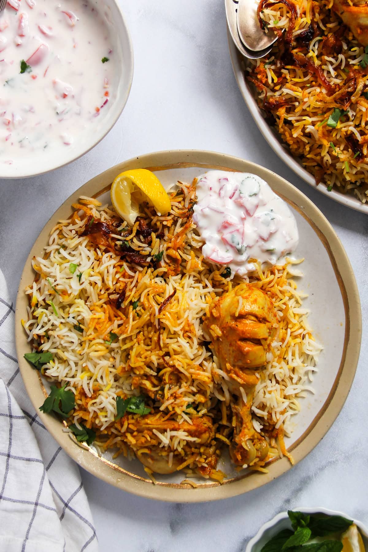 chicken biryani served with raita and lemon wedge. 