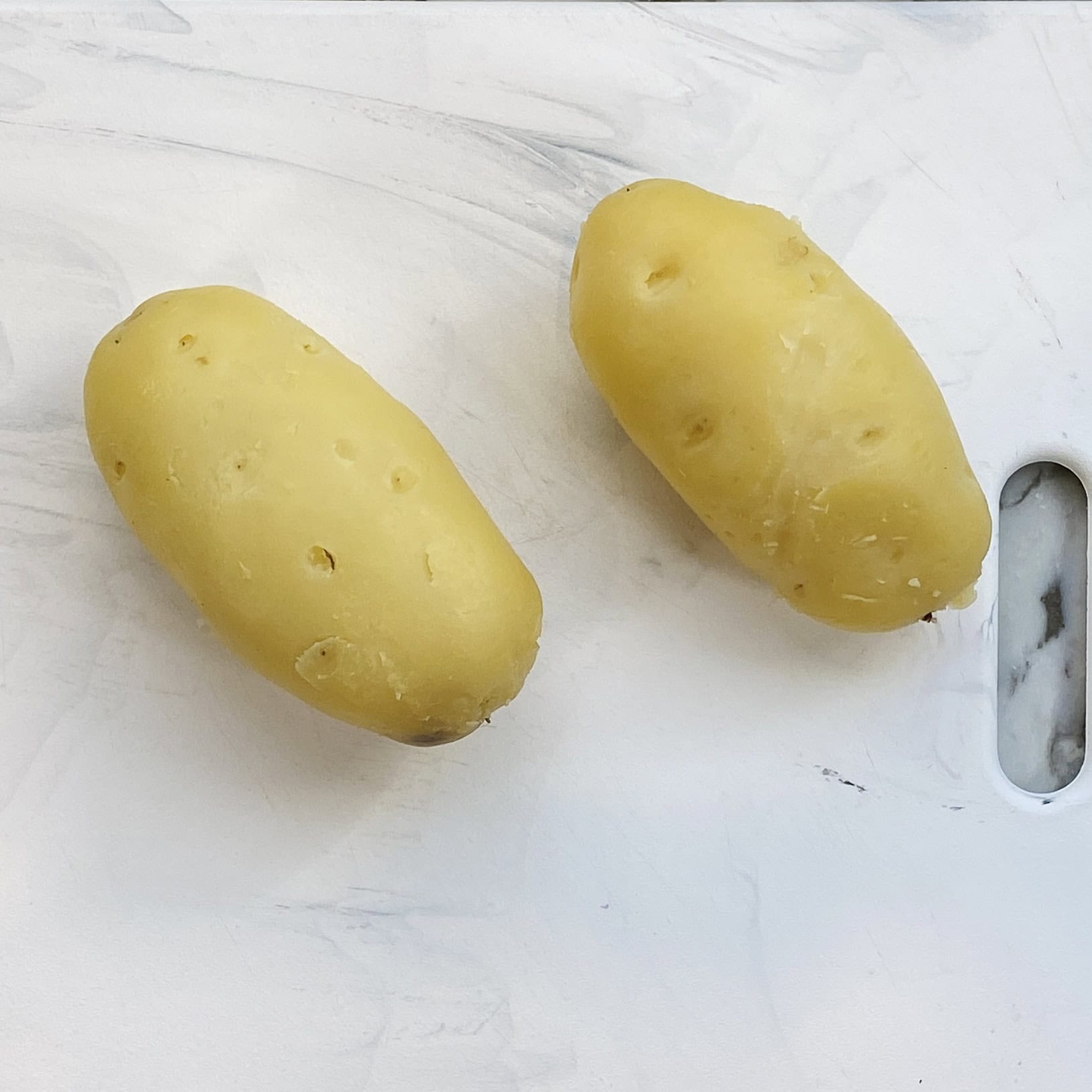 peeled potatoes on a cutting board