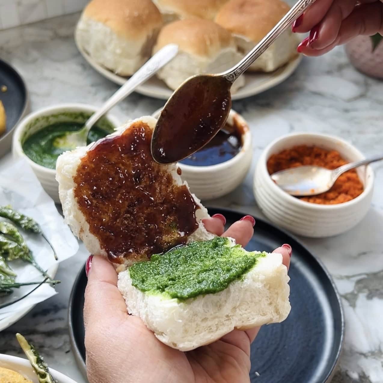 spreading green chutney and tamarind chutney inside pav 