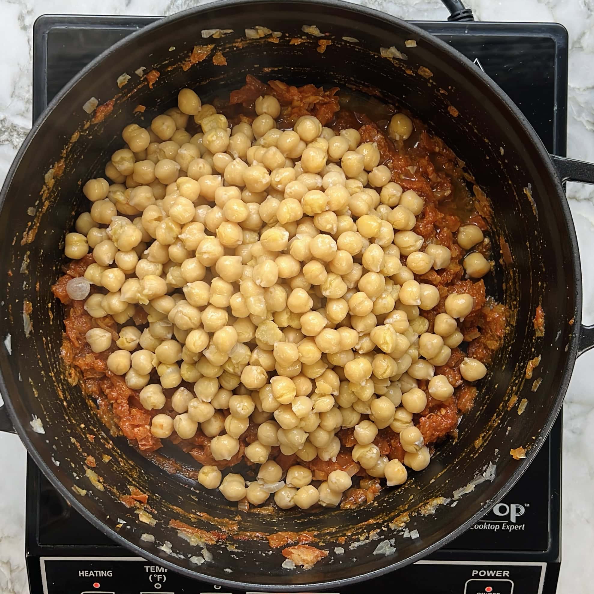 boiled chickpeas added to the pot of masala 