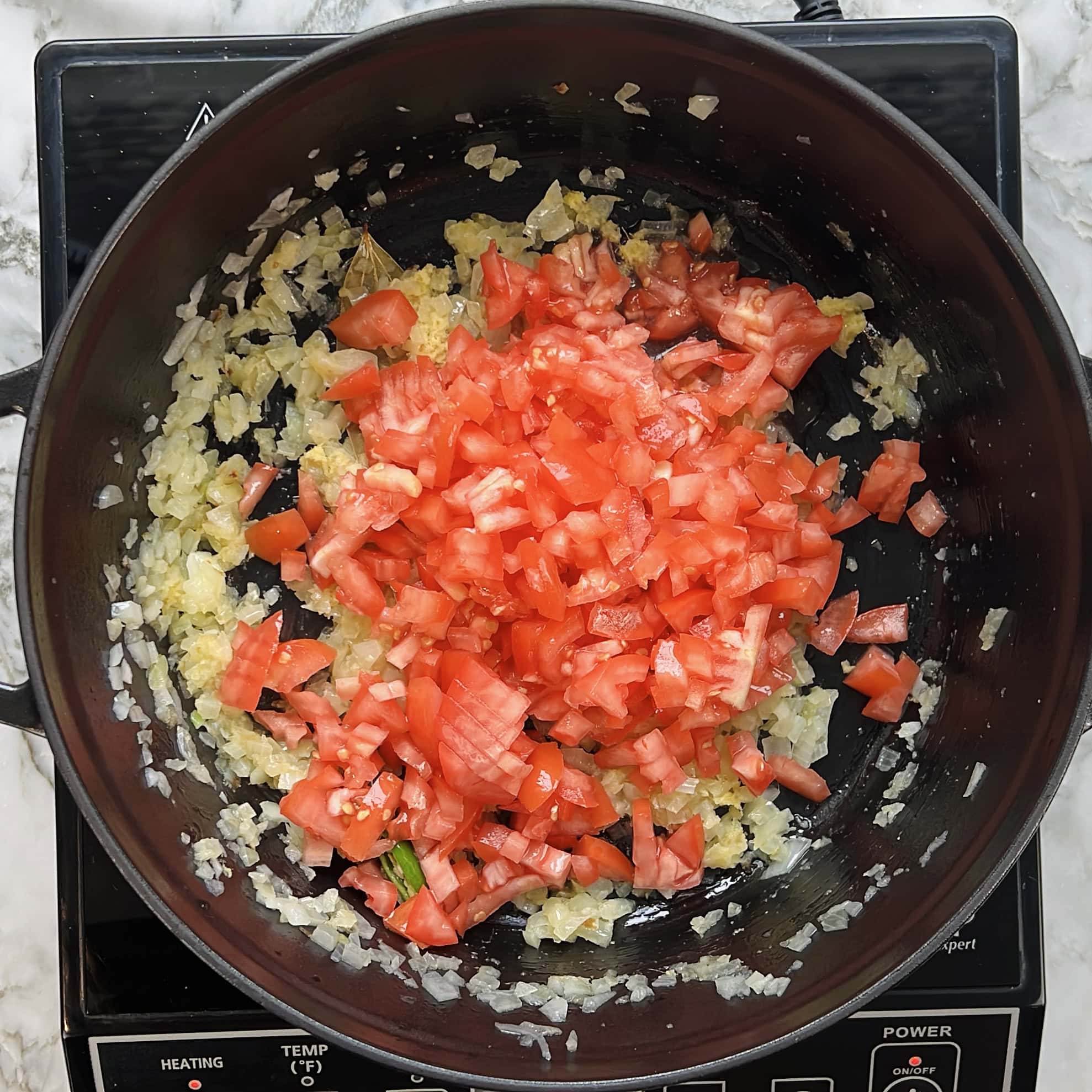 sateed onions and diced tomatoes in a pan 