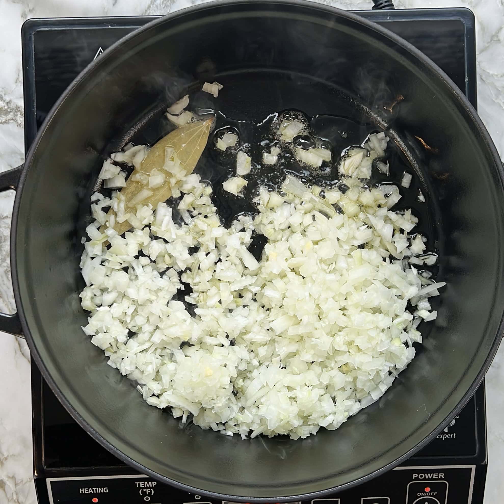 onion and bayleaf in a cast iron pan 