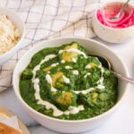 palak chicken garnished with cream in a serving bowl