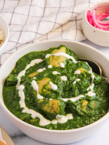 palak chicken garnished with cream in a serving bowl