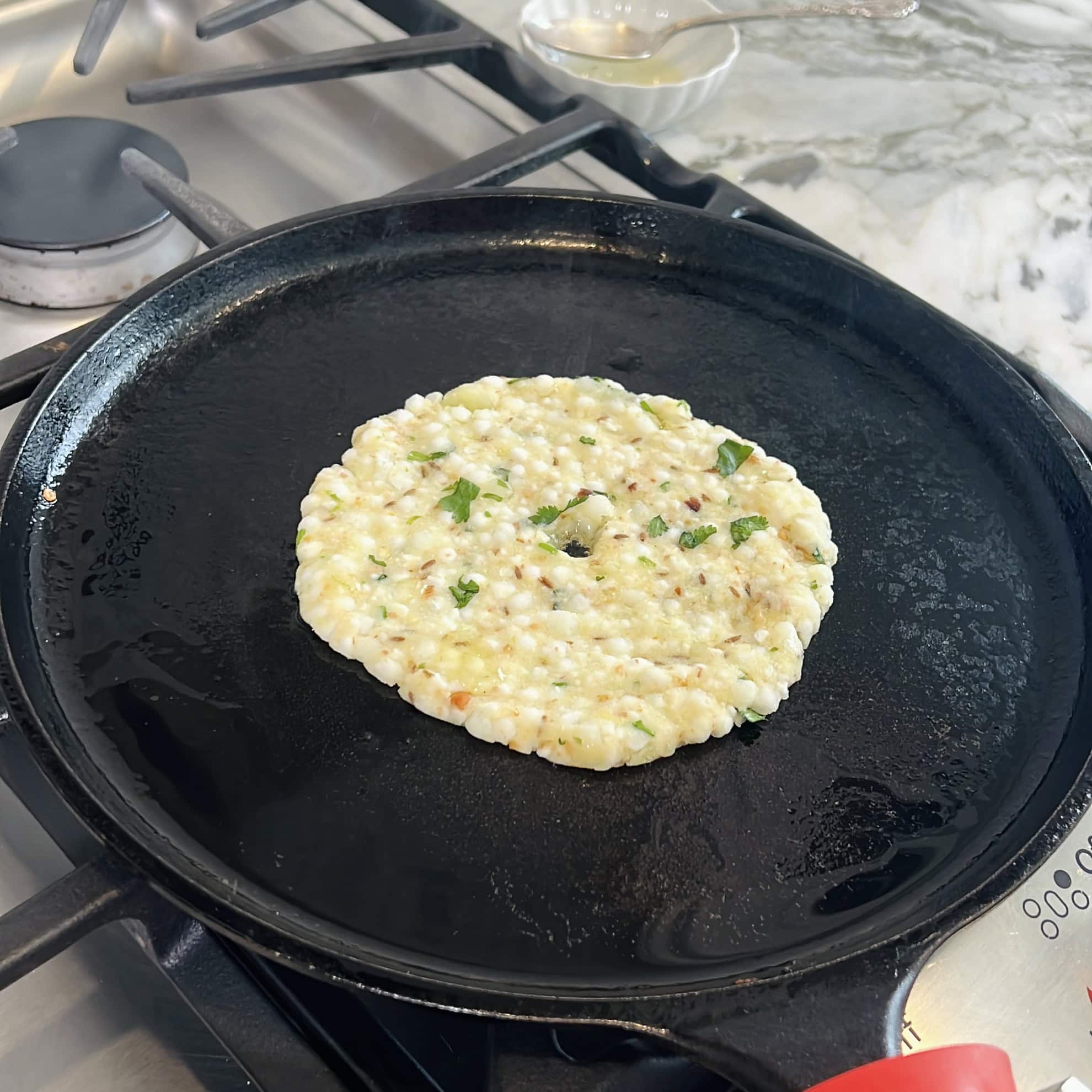 pressed sabudana thalipeeth on a cast iron pan 