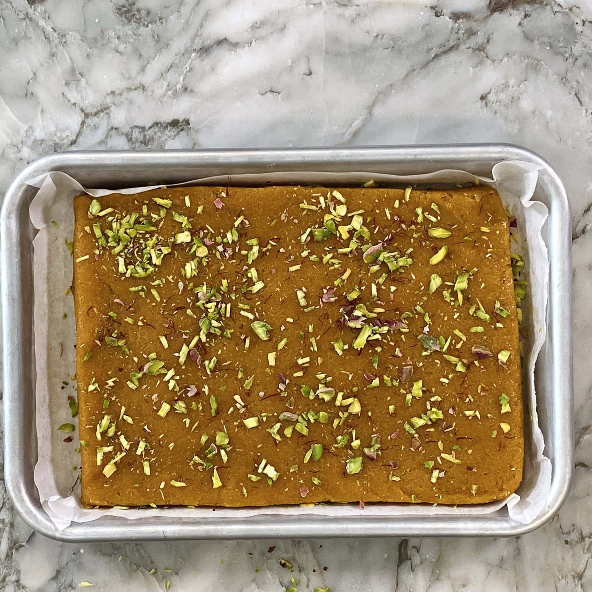 mango coconut burfi garnished with pistachios and saffron