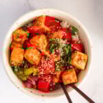 chilli tofu in a white bowl garnished with sesame seeds