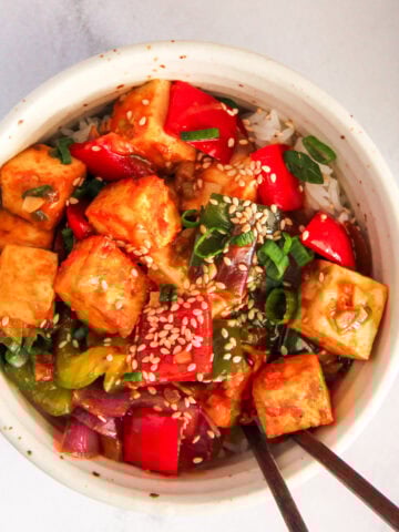 chilli tofu in a white bowl garnished with sesame seeds