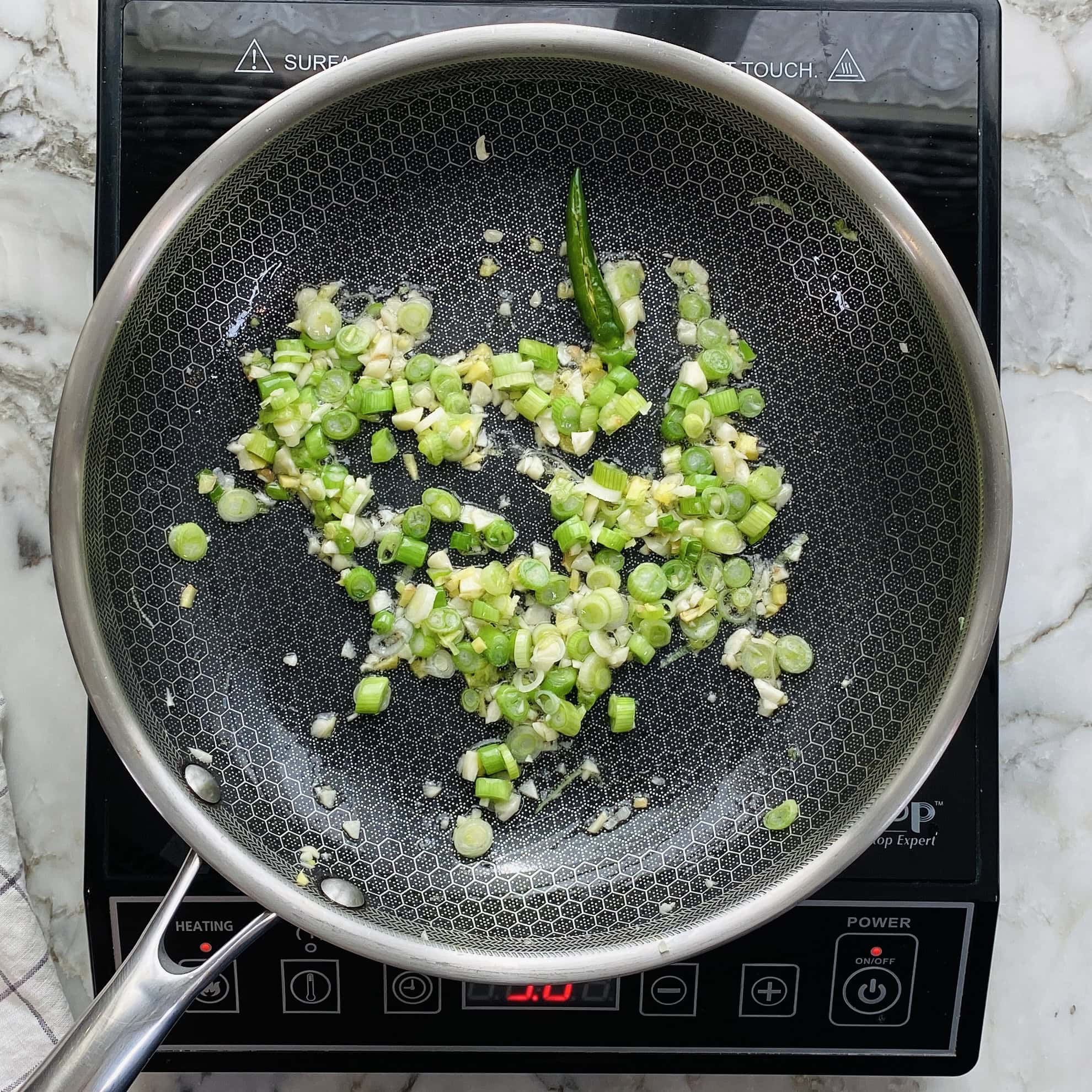 sauteeing scallion and chili in a pan 
