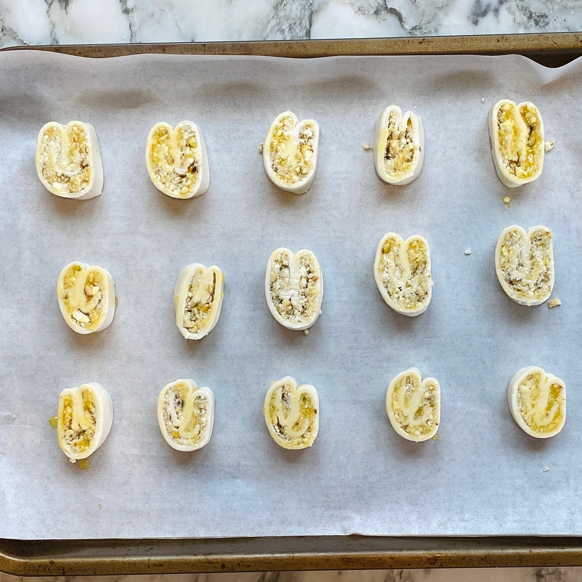 gujiya bites brushed with butter ready to bake in a baking tray.