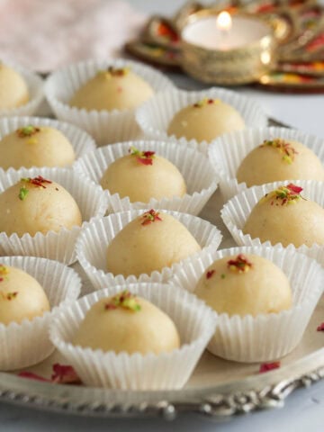 malai laddus garnished with pistachios and rose petals.