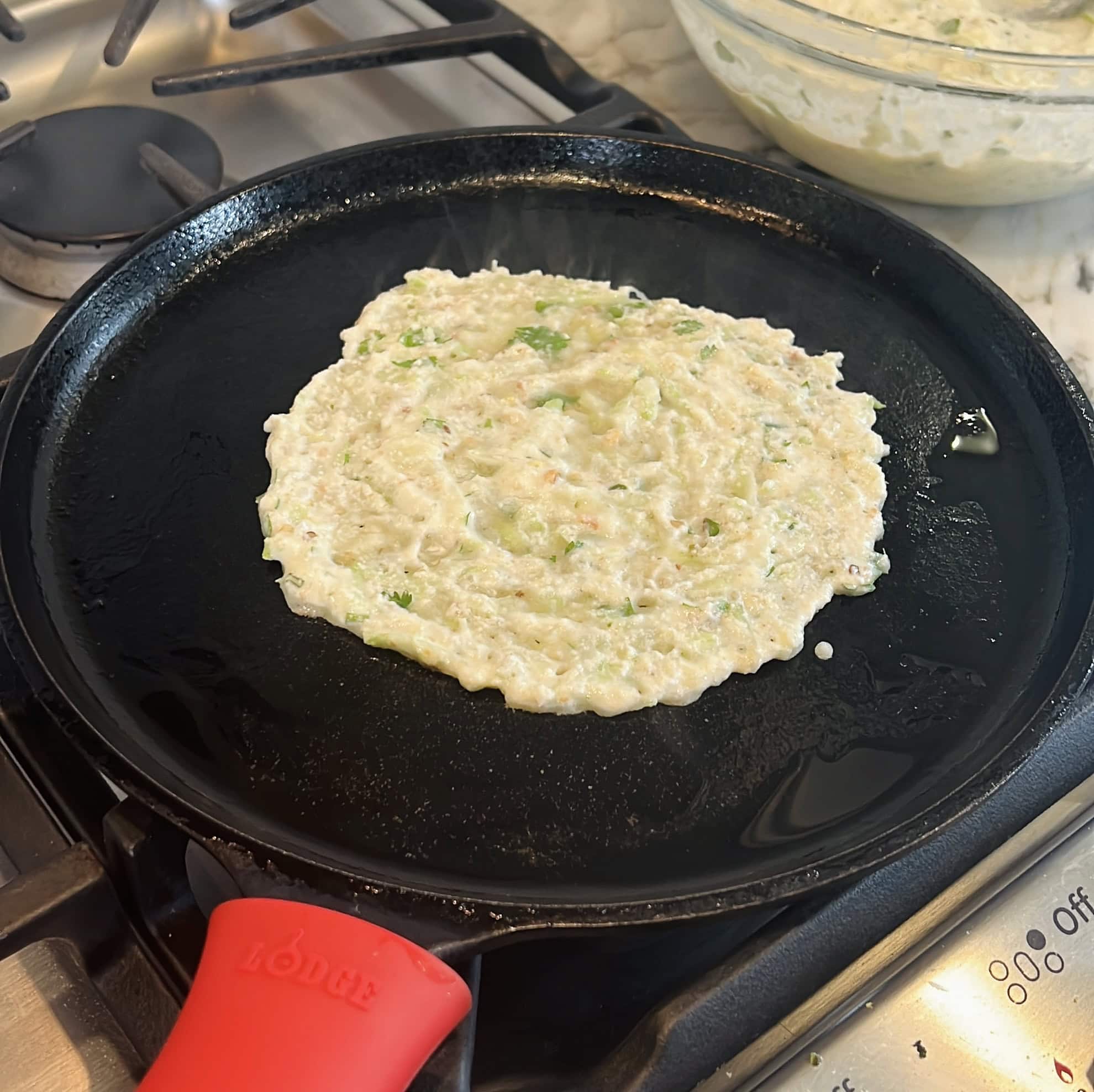 dudhi dhirde batter spread on a cast iron pan.