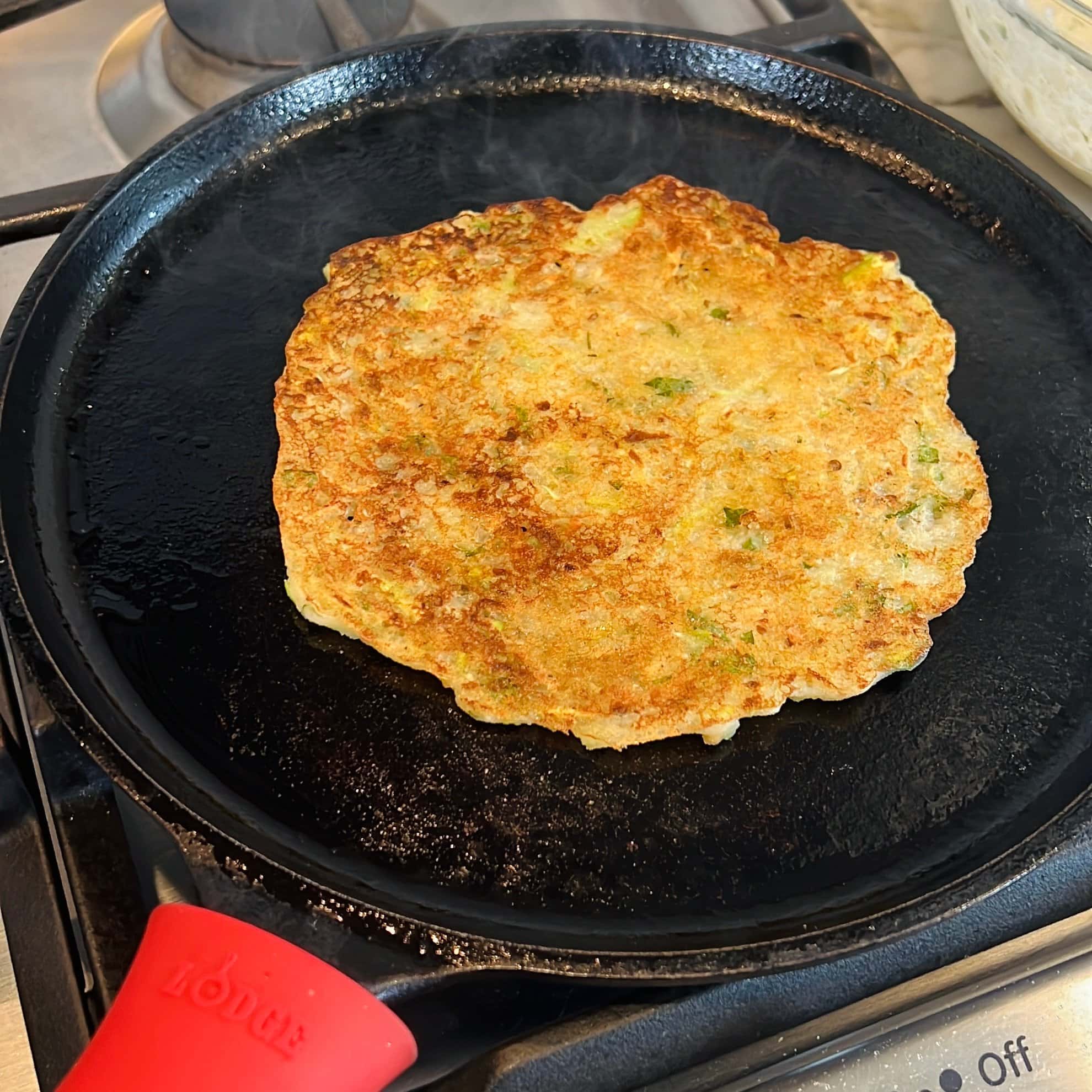 dudhi dhirde cooking on a cast iron pan.