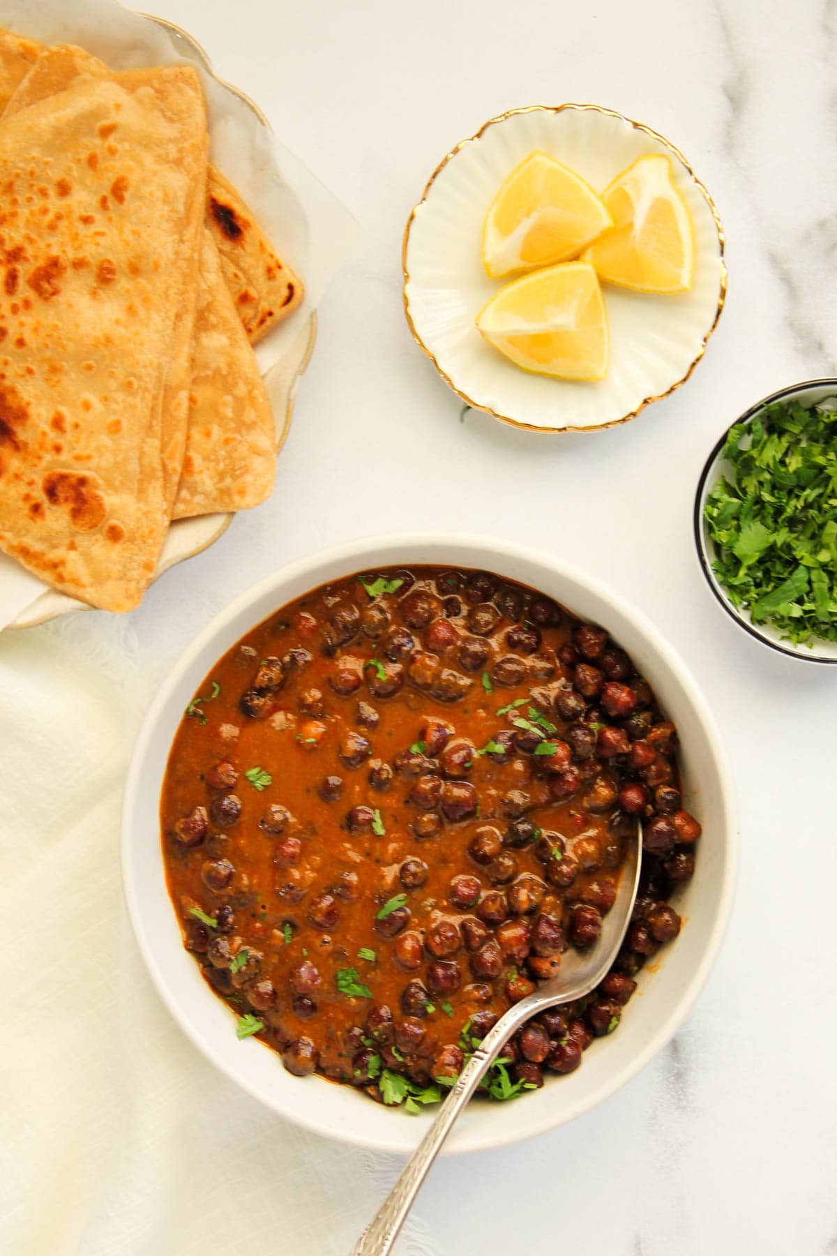 kala chana curry served with parathas and lemon wedges 