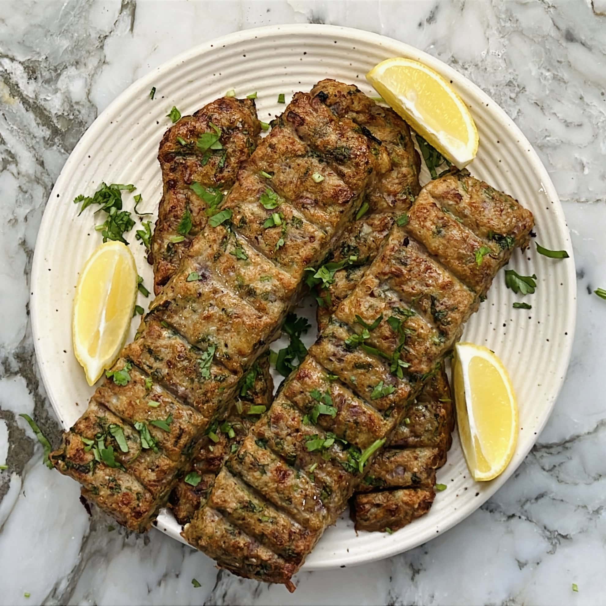 chicken kebabs garnished with cilantro and sevred with lemon wedges. 