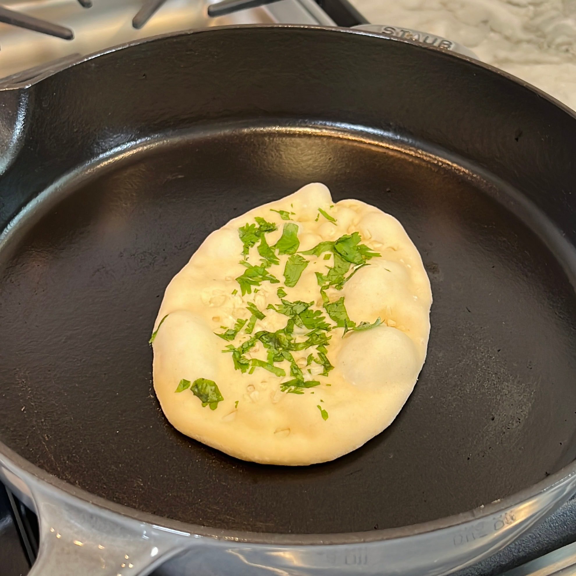 bubbly naan on a cast iron skillet
