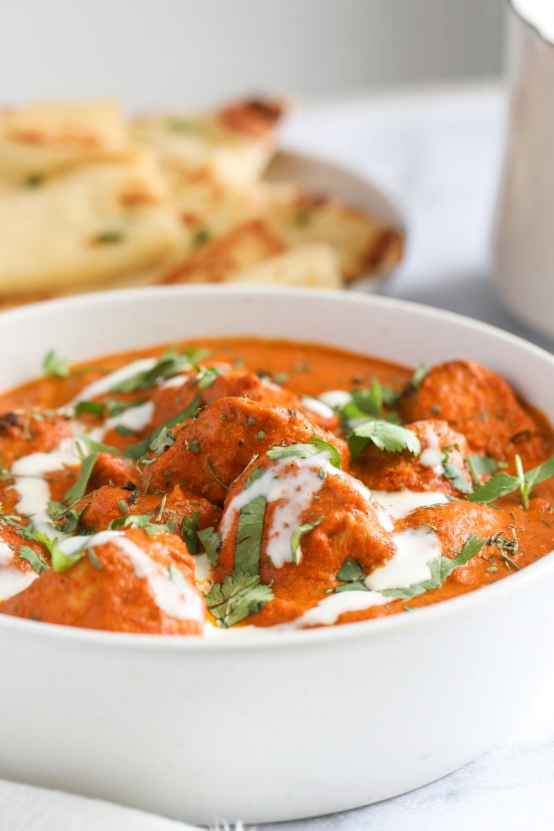 closeup photo of chicken tikka maslaa in a white bowl.