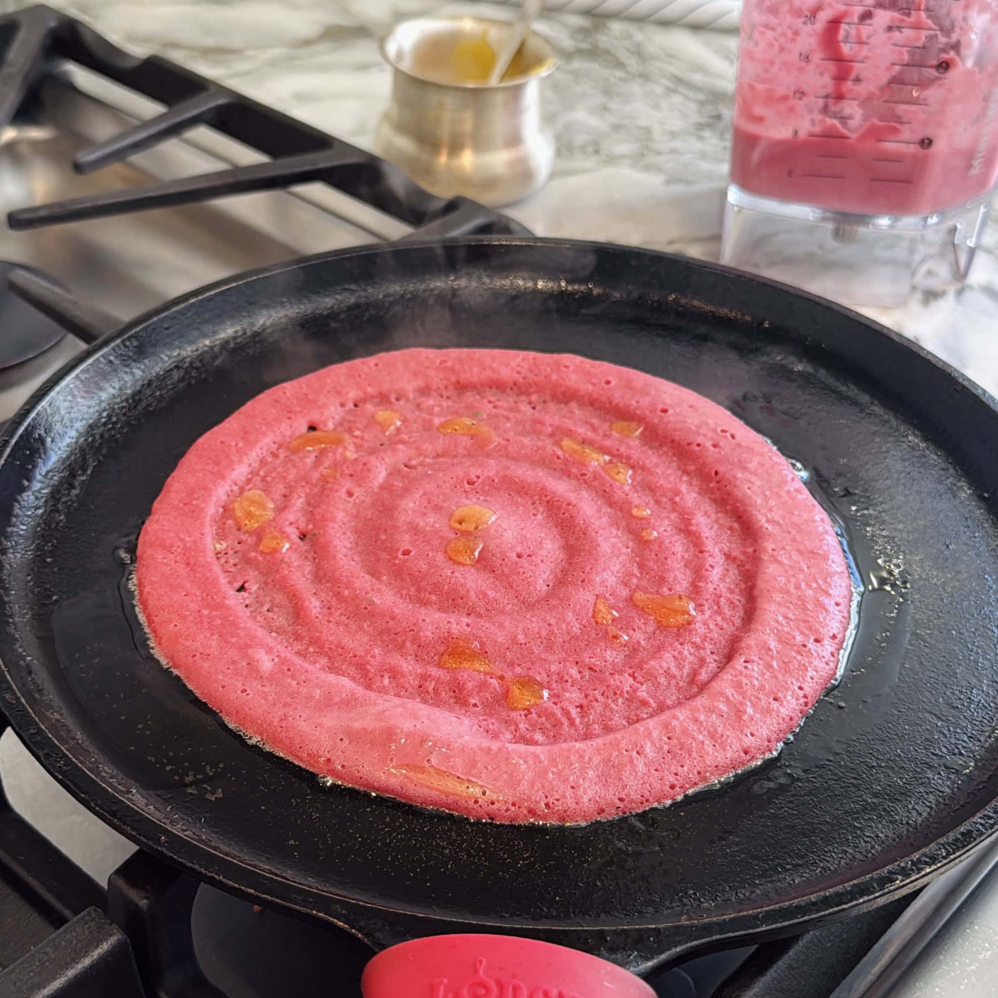 beet chilla batter spread on a cast iron pan.