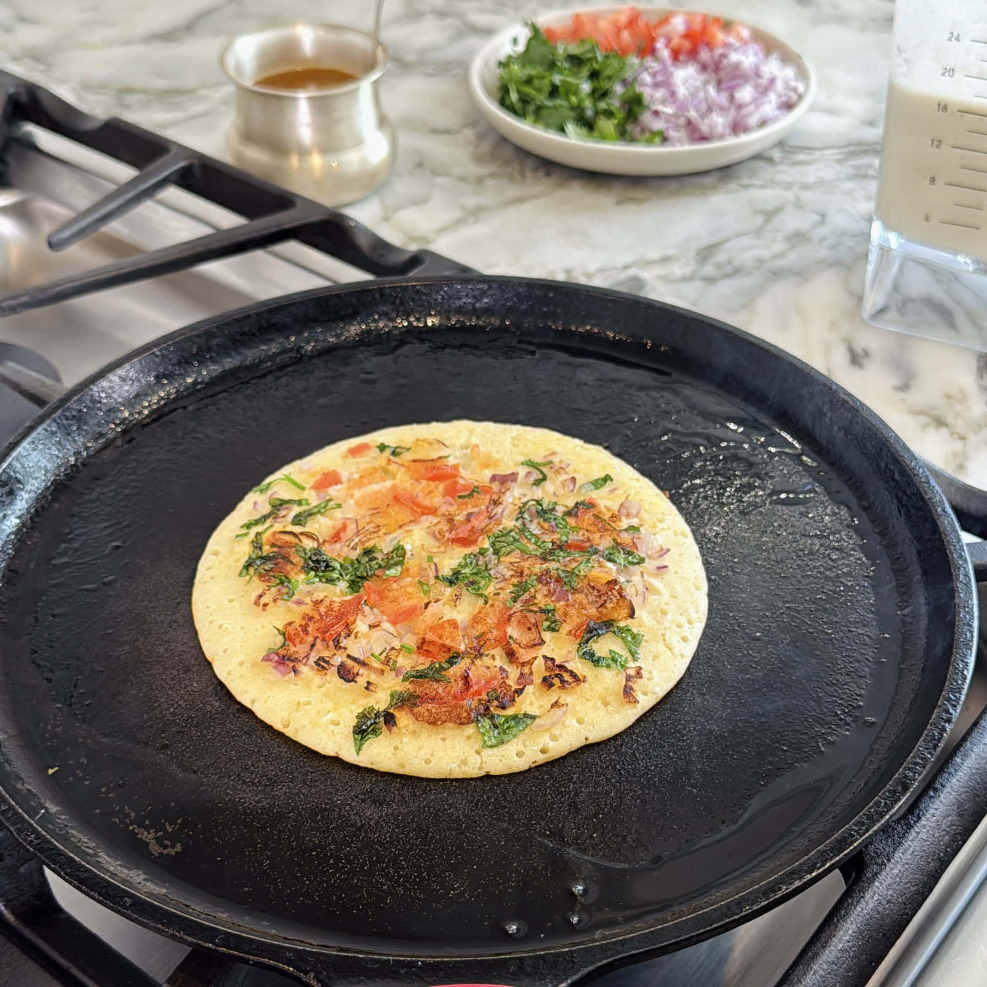 protein uttapam with onion, tomato and cilantro. 